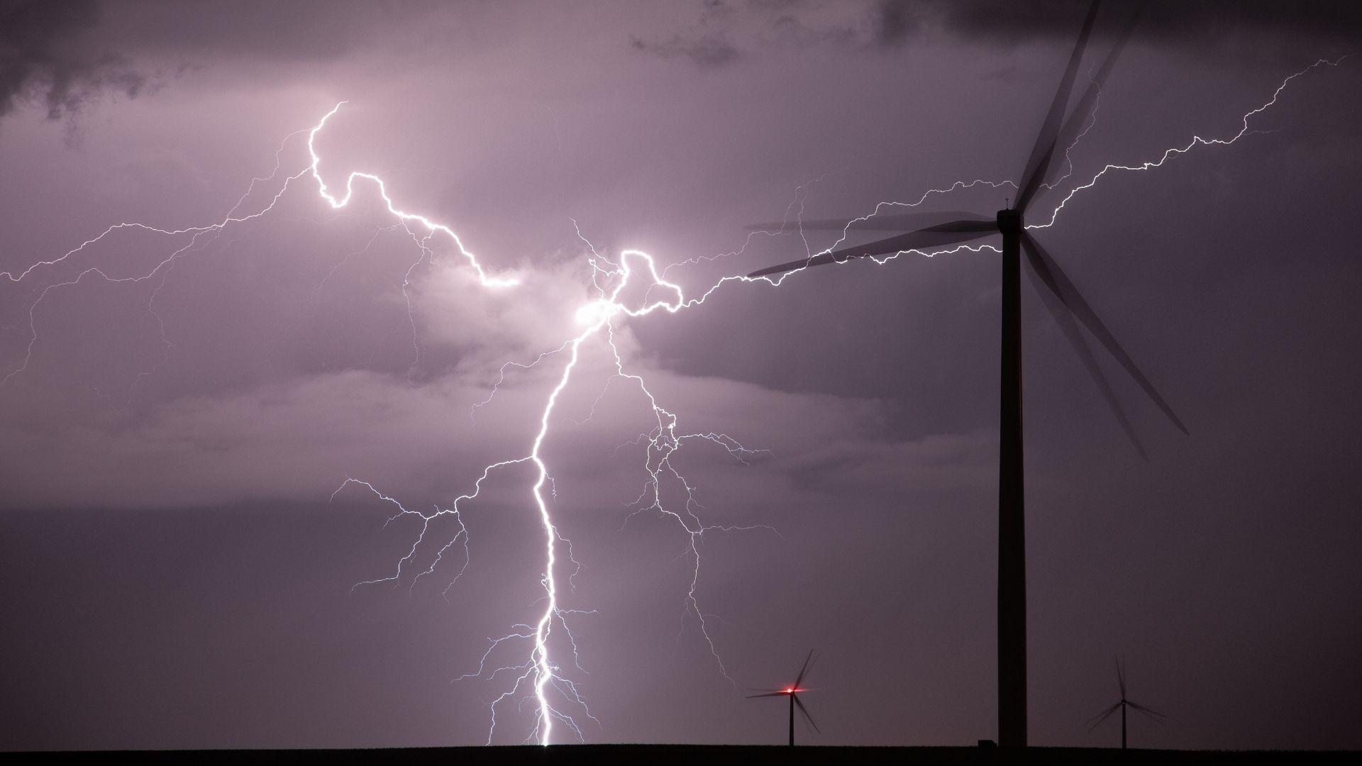 Wind turbines by night with a big lightning strike.