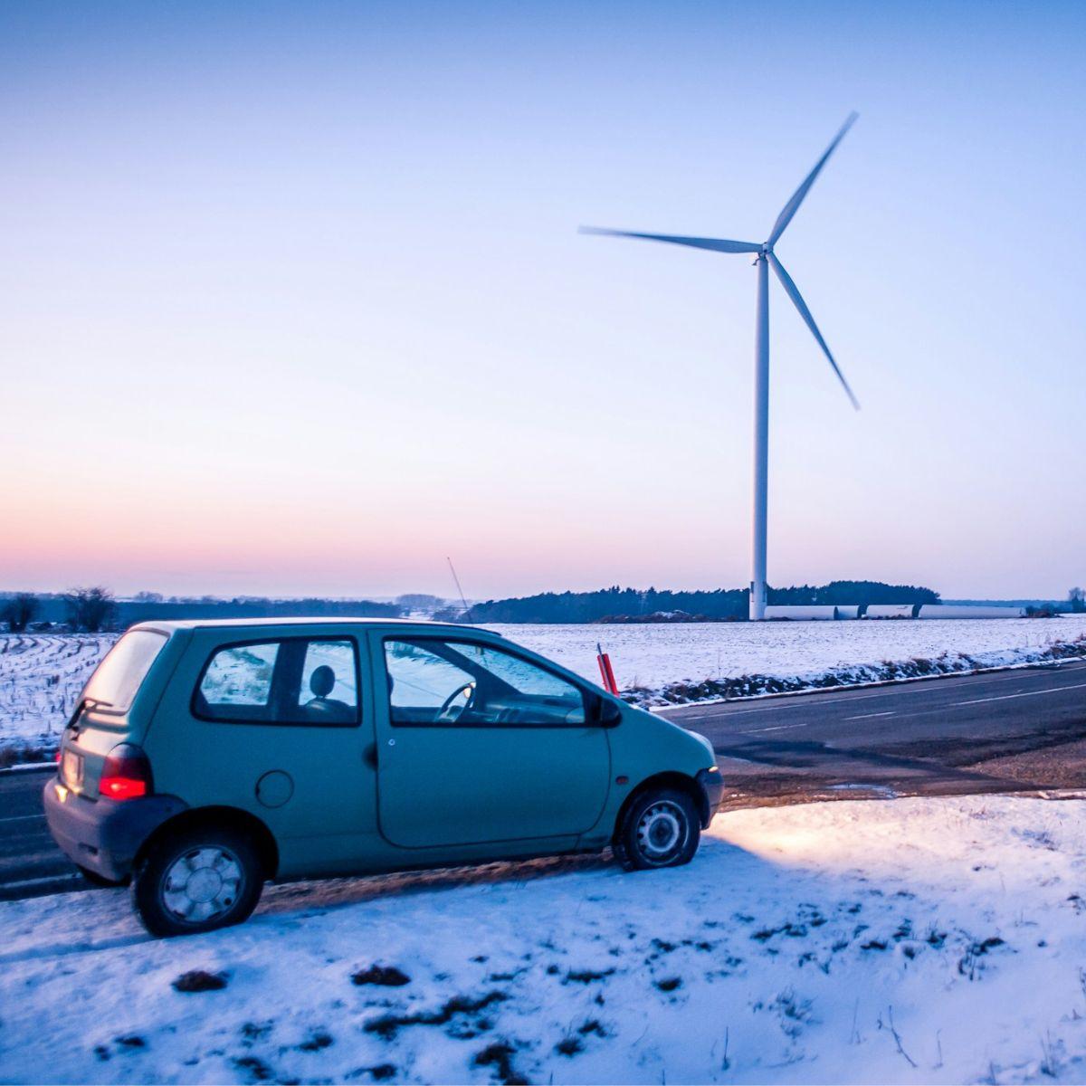 Blue car in front of a wind turbine