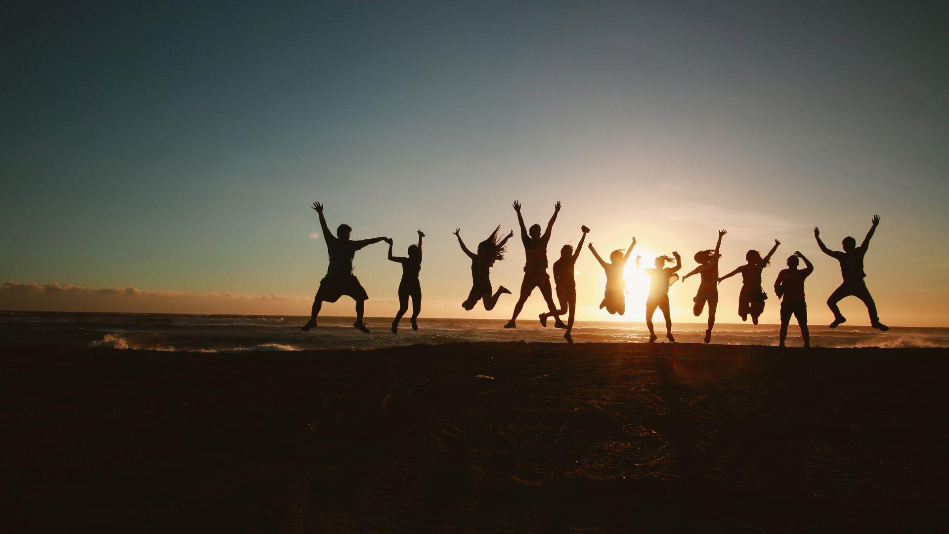 Group jumps in front of a sunset