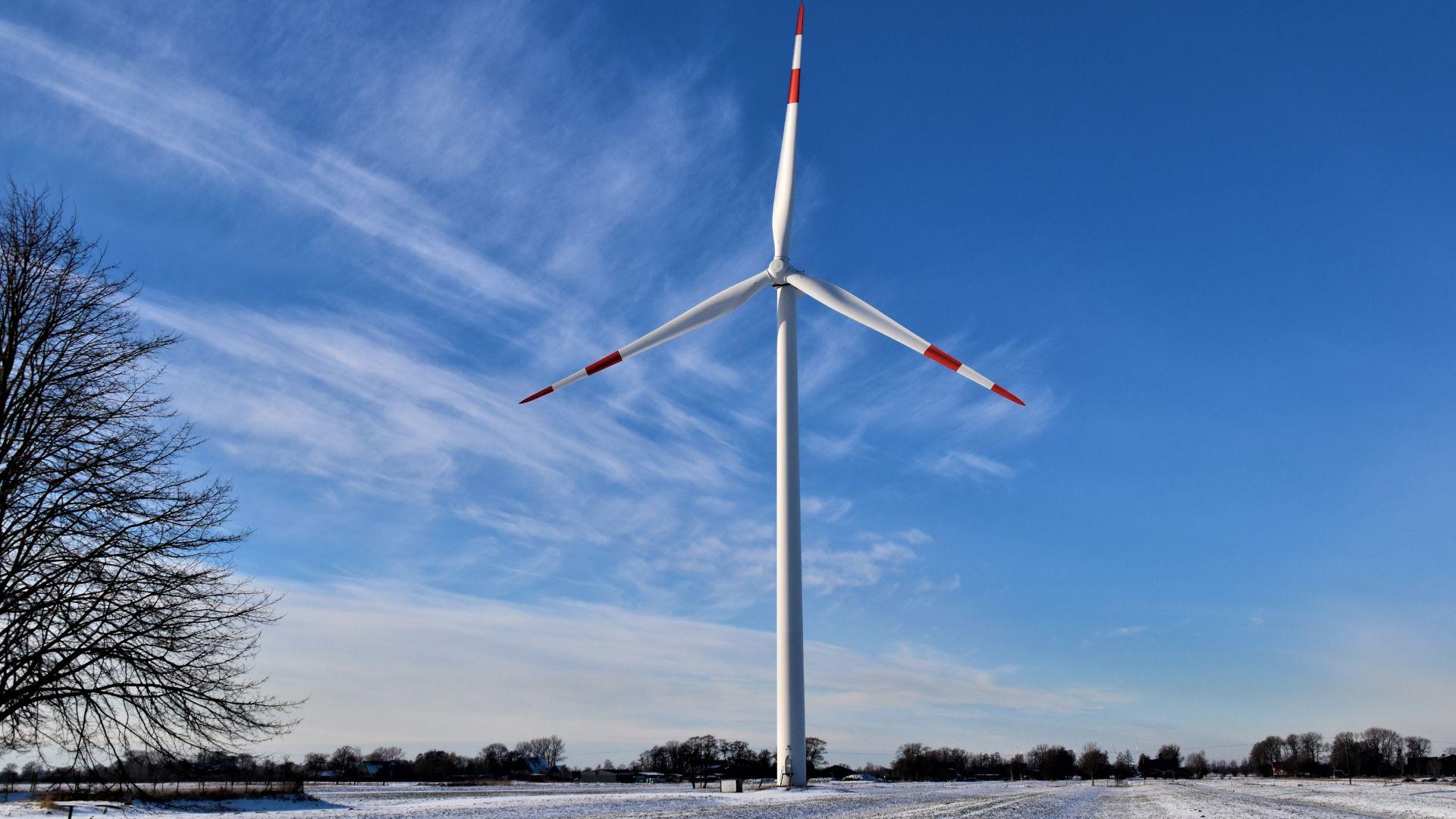 Winter landscape with a white wind turbine in the middle.