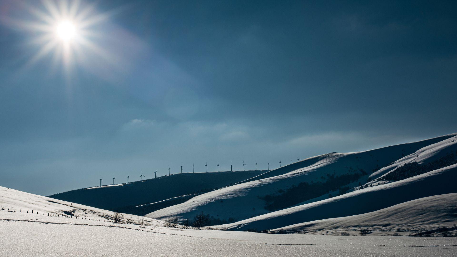 Snowy landscape in winter with wind turbines on the horizon